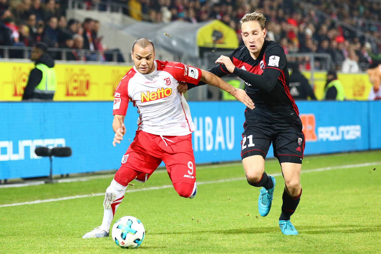 Jann George kämpft mit Tobias Schröck um den Ball. Jetzt auf Regensburg gegen Ingolstadt wetten.